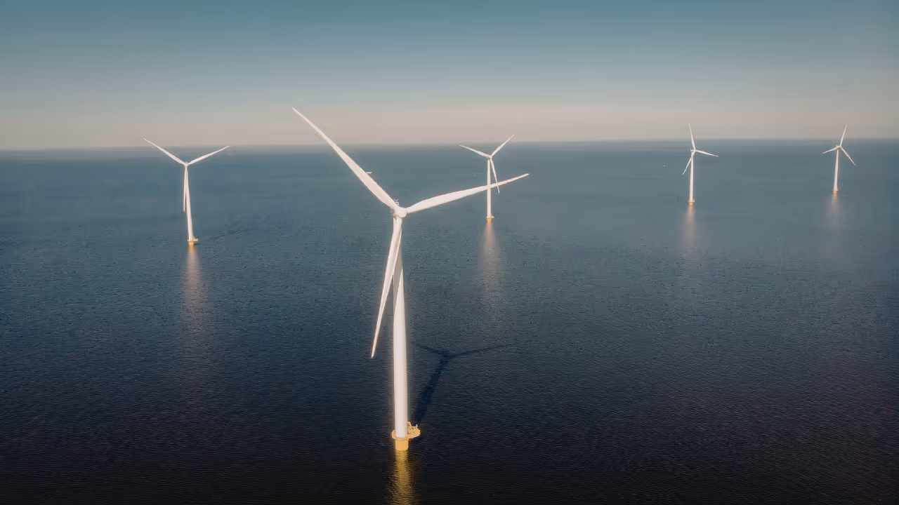 Offshore wind turbines standing in the ocean with clear sky above.