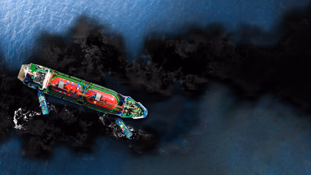 Aerial view of a large tanker ship surrounded by three smaller boats on dark blue water.